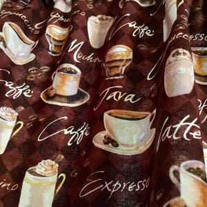 May include: Brown fabric with a repeating pattern of coffee cups, coffee beans, and coffee-related words like "caffe", "latte", and "espresso". The background has a checkered design.