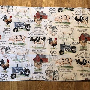 May include: A white fabric with a repeating pattern of farm animals, including cows, pigs, sheep, and chickens. The design also features red barns, tractors, and text that reads "Dairy Farm Artisan Produce" and "Eggs for Sale".