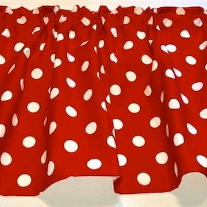 May include: Red valance with white polka dots. The valance is made of a soft, fabric and has a ruffled edge.