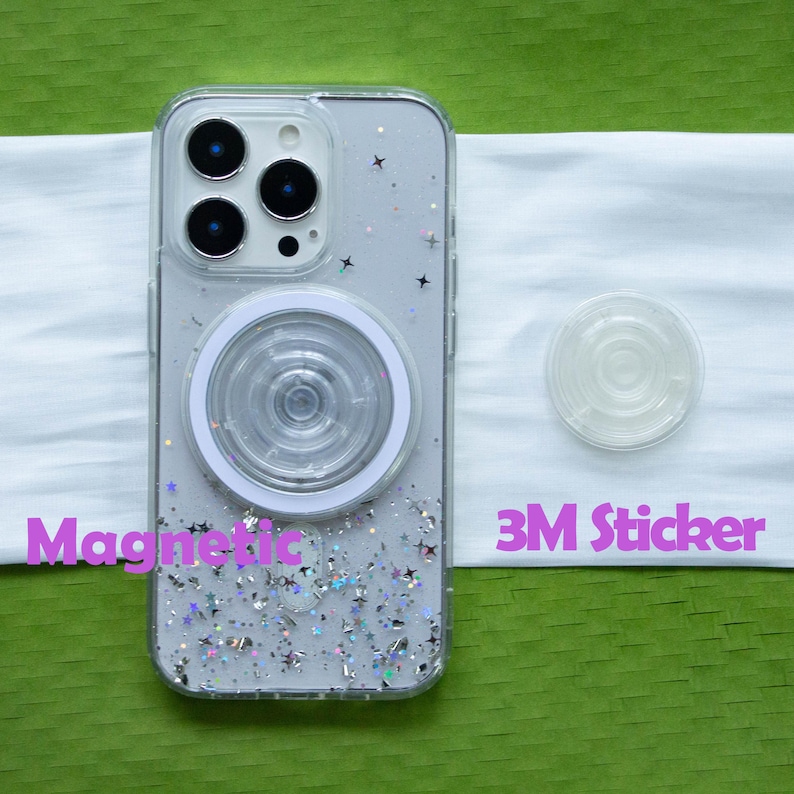 May include: A clear smartphone case with silver star-shaped glitter and a circular magnetic ring attachment on the back. Beside the case is a separate circular adhesive component labeled 3M Sticker. The text Magnetic is visible.