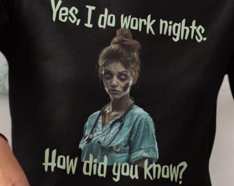 May include: Black long-sleeve shirt with the text "Yes, I do work nights. How did you know?" and a graphic of a zombie nurse. The shirt is made of a soft material.
