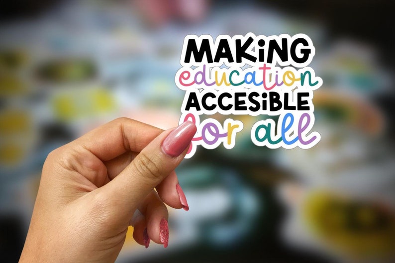 May include: A white sticker with the text "MAKING education ACCESSIBLE for all" in colorful letters. The sticker is being held by a hand with pink nail polish.