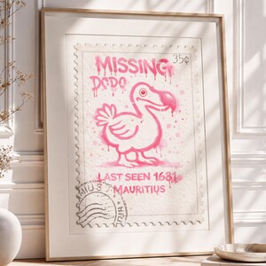 Op de afbeelding: Ingelijste kunstdruk met een roze illustratie van een dodo op een postzegelontwerp. De tekst "MISSING DODO" en "LAST SEEN 1681 MAURITIUS" zijn roze. Het kunstwerk zit in een houten lijst.
