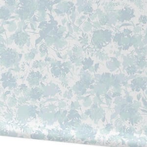 May include: A roll of wallpaper featuring a repeating floral pattern in shades of blue and green on a white background. The design includes various flower shapes and foliage, creating a soft, watercolor effect. The wallpaper is partially unrolled, showing the pattern.