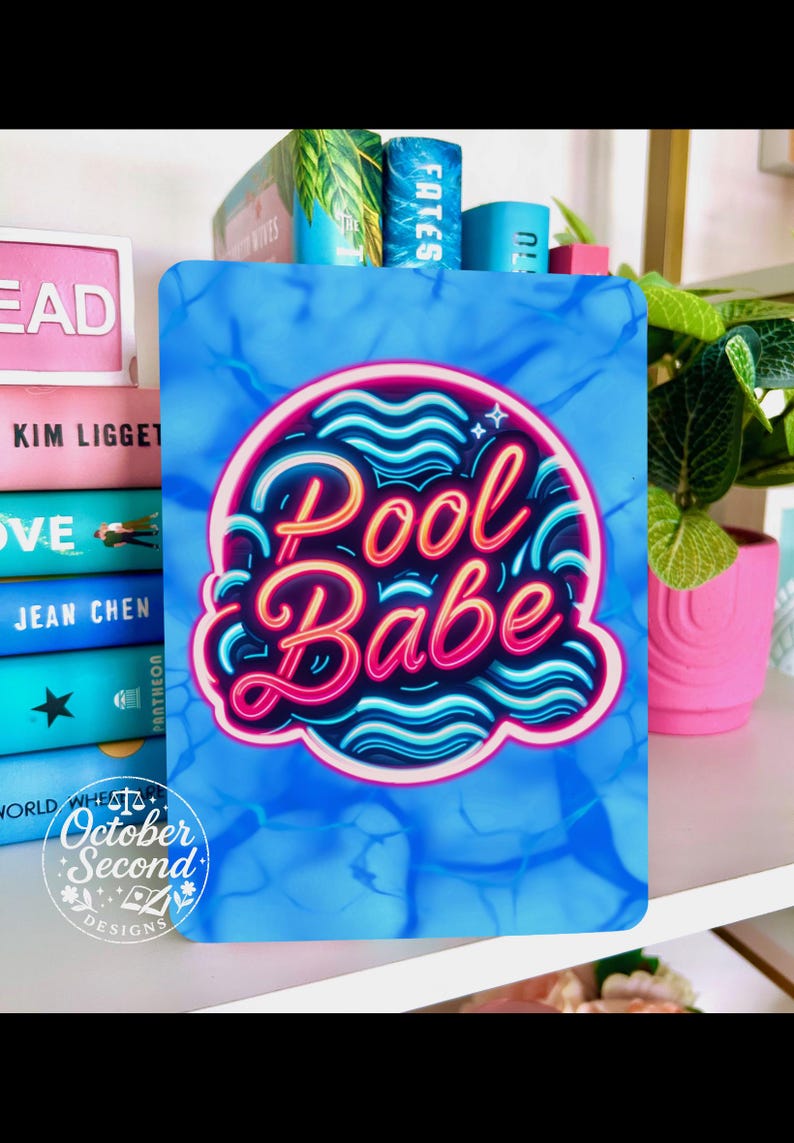 May include: A blue rectangular sign with the words "Pool Babe" in a neon-style design. The sign has a water-like background and is surrounded by books and a pink flower pot.