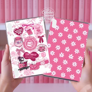 May include: Two pink iPad cases. One case features a floral design with book-themed graphics and text, including "Emotional Support iPad" and "Anti Social Book Club." The other case has a pink background with white daisy patterns.