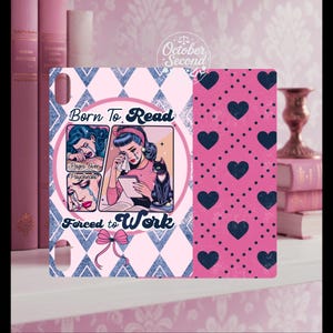May include: A decorative item with a pop art style design. The item features the text "Born to Read, Forced to Work" and an illustration of a crying woman with a black cat. The background has a pink and blue diamond pattern and a pink heart pattern.
