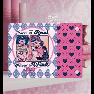 May include: A decorative sign with a pink and blue design. The sign features a retro illustration of a woman crying, with the text "Born to Read, Forced to Work." A black cat sits beside the woman. The right side of the sign has a pink heart pattern.