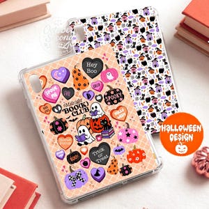 May include: Two clear tablet cases featuring Halloween-themed patterns. One case has a peach background with heart-shaped candies, ghosts reading books, pumpkins, and the text Midnight Book Club. The other case has a white background with small icons of witches, black cats, pumpkins, and cauldrons.