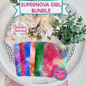 May include: A collection of colorful galaxy-themed inserts, displayed on a white tray with floral arrangements. The inserts feature vibrant patterns in shades of purple, red, blue, and green. Text on the image reads "Supernova Girl Bundle" and "October Second Designs".