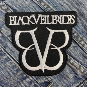 Könnte beinhalten: Schwarzer Aufnäher mit dem weißen Schriftzug "BLACK VEIL BRIDES" oben. Darunter befindet sich ein weißes "VB"-Emblem. Der Aufnäher ist rechteckig mit einer gebogenen Unterkante.