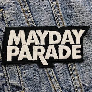 Puede incluir: Parche rectangular negro con las palabras "MAYDAY PARADE" bordadas en blanco. El parche está sobre una chaqueta vaquera.