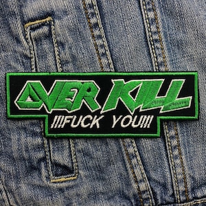 Puede incluir: Parche bordado rectangular con la palabra "OVER KILL" en verde, contorneada en blanco, sobre fondo negro. Debajo, "!!!FUCK YOU!!!" en blanco. El parche está sobre una chaqueta vaquera.