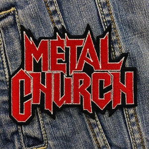 Puede incluir: Parche bordado con las palabras "METAL CHURCH" en rojo con contorno negro y borde dentado. El parche está sobre un fondo de tela vaquera azul.
