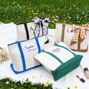 Può includere: Quattro borse di tela con testo e dettagli personalizzati. Una borsa ha manici neri e un fiocco bianco e nero, un'altra ha manici marroni e una sciarpa floreale, e due hanno finiture colorate. Una dice "Sophia Damigella d'onore".