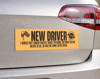 May include: An orange rectangular bumper sticker with the words "NEW DRIVER" in bold black letters. The sticker also includes a car key graphic and the text: "I WOULD SAY I KNOW EXACTLY WHAT I'M DOING, BUT MOM TOLD ME NEVER TO LIE, SO GIVE ME SOME EXTRA SPACE."