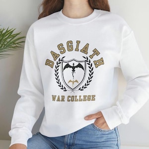 May include: White sweatshirt with a gold graphic of a dragon and shield with the text "Basgiath War College".