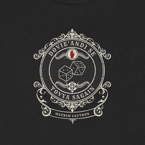 May include: Black t-shirt with a white crest featuring a hand, dice, and the text "Dovie's Andise Toyya Sagain Matrim Cauthon".