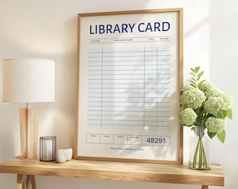 May include: A framed print of a library card with blue lines and text. The words "LIBRARY CARD" are at the top, with fields for "DATE DUE," "BORROWER'S NAME," "TITLE," and "AUTHOR." The print is displayed on a wooden table.