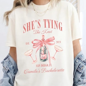 Bachelorette Party Shirts, She&#39;s Tying the Knot Shirt, Bridal Party Gift, Coquette Bow Bachelorette Shirt, Custom Location Luxury Bach Merch