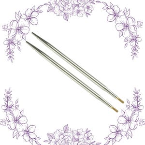 May include: Two silver knitting needles with pointed tips. The needles are straight and parallel, with a slight taper towards the ends. The tips are a brassy gold color. The background is white with purple floral accents.
