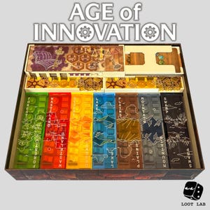 Puede incluir: Un organizador de juegos de mesa con el texto "AGE of INNOVATION" en la parte superior. El organizador tiene compartimentos con divisores coloridos etiquetados como "FOREST", "WASTELAND", "DESERT", "LAKE", "PLAINS", "MOUNTAIN" y "SWAMP".