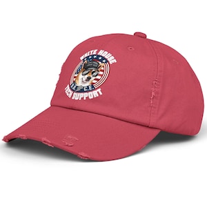 Puede incluir: Gorra de béisbol roja desgastada con un logotipo de soporte técnico de la Casa Blanca que presenta un corgi de dibujos animados con un sombrero militar y gafas de sol. El logotipo está rodeado por un círculo rojo, blanco y azul con estrellas y rayas.