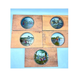 May include: Five antique miniature paintings set in wooden frames. Each painting, framed in gold, depicts scenes with figures, horses, and landscapes. The wooden frames have a natural wood grain finish, and the paintings are set against a light blue background.
