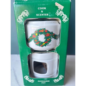 May include: A white ceramic Cook N Scenter potpourri pot in a green cardboard box. The pot features a colorful wreath illustration of fruits and leaves. The box displays the text Cook N Scenter and Potpourri Pot with white decorative scrollwork.