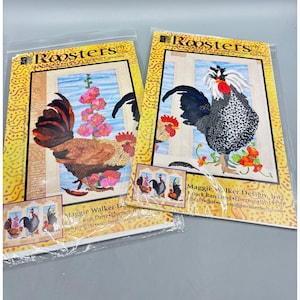 May include: Two packaged needlepoint kits with rooster designs. One shows a brown and red rooster with pink flowers, the other a black and white rooster with orange flowers. The kits are labelled "Roosters".