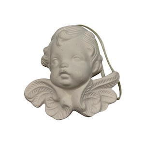 May include: A white cherub ornament with a serene expression, featuring detailed wings and a loop for hanging. The cherub's face has delicate features and curly hair. The ornament is made of a matte, off-white material.