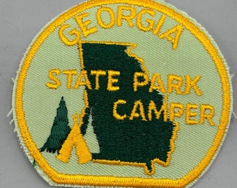 May include: A yellow and green embroidered patch with the text "Georgia State Park Camper" and an outline of the state of Georgia.