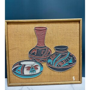 May include: A framed string art piece on a tan burlap background featuring three vessels. The artwork displays a tall vase, a wide bowl, and a smaller pot, all decorated with geometric patterns in red, black, white, and turquoise thread.
