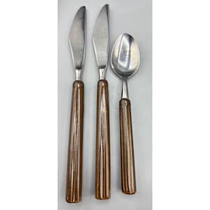 Può includere: Set di tre posate vintage in acciaio inossidabile: due coltelli e un cucchiaio. Le posate hanno manici marroni e scanalati. Le lame e la conca del cucchiaio sono argentate. Il set è probabilmente per la cena.