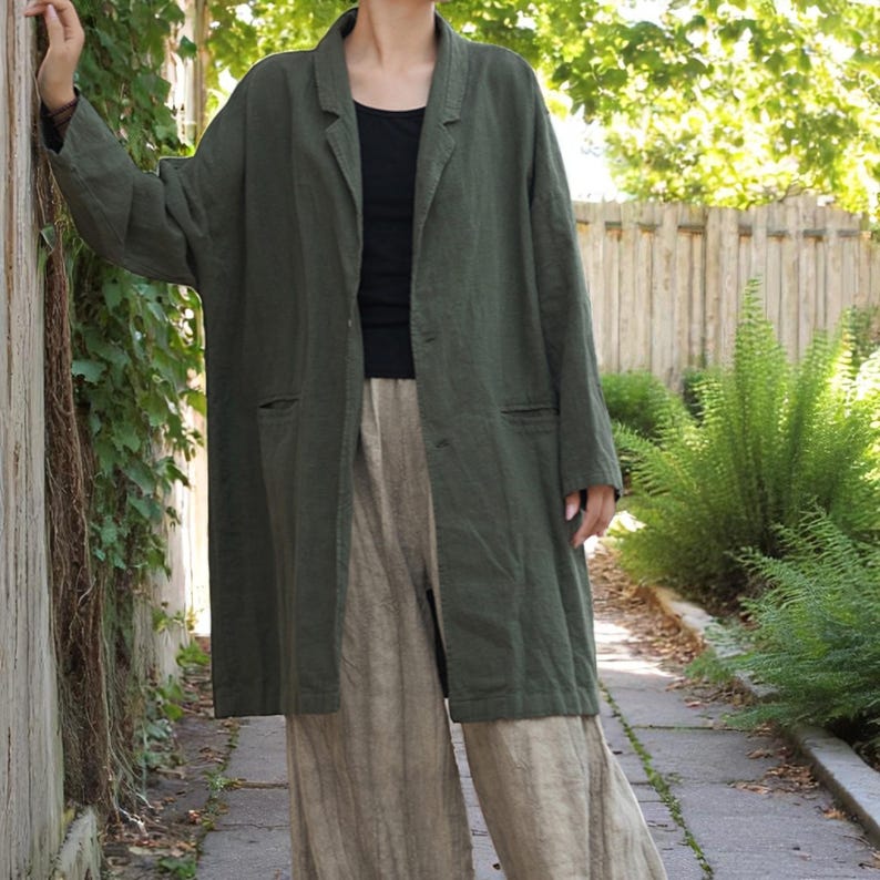 Peut inclure: Un long manteau en lin vert olive avec un col &agrave; revers et deux poches avant. Le manteau est port&eacute; sur un haut noir et associ&eacute; &agrave; un pantalon en lin beige. La tenue est d&eacute;contract&eacute;e et confortable, adapt&eacute;e au quotidien.
