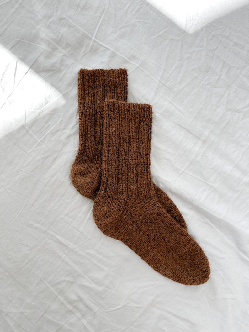 May include: A pair of brown knitted socks on a white background.
