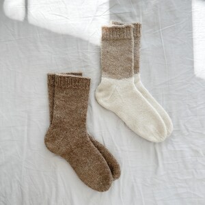 K&ouml;nnte beinhalten: Zwei Paar Stricksocken, ein Paar ist braun und das andere ist wei&szlig; mit braunem Oberteil.