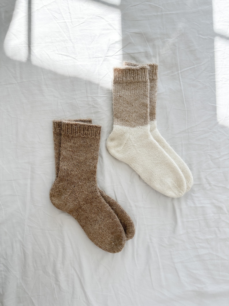 K&ouml;nnte beinhalten: Zwei Paar Stricksocken, ein Paar ist braun und das andere ist wei&szlig; mit braunem Oberteil.