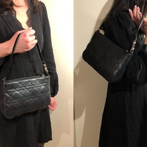 May include: A black quilted leather handbag with a silver chain strap. The bag has a flap closure and a small, rectangular shape.