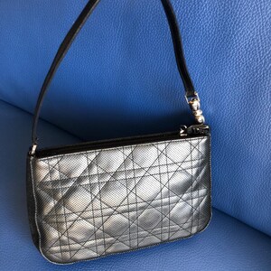 May include: A black quilted handbag with a silver zipper and a small silver charm that says "Dior".