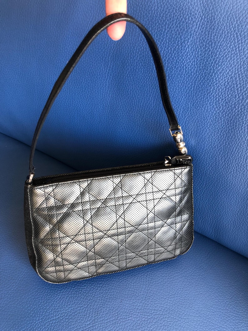 May include: A black quilted handbag with a silver zipper and a small silver charm that says "Dior".