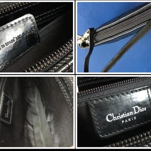 May include: Black leather purse with a silver clasp and a zipper closure. The purse has a black leather strap and a label that reads "Christian Dior Paris" and "Made in Spain MC 0027".