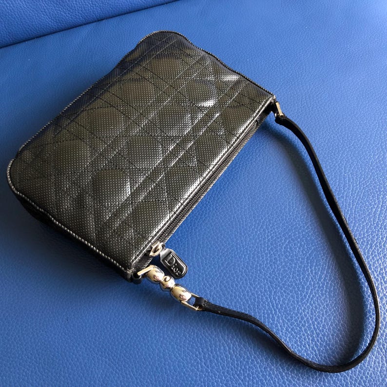 May include: A black quilted leather handbag with a silver zipper and a short strap. The bag has a subtle diamond pattern.