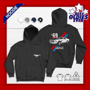 May include: Black hoodie featuring a white Mustang logo on the front and a graphic of a '69 Mustang with the text "AMERICAN" on the back. The hoodie has a hood and a front pocket. The design includes red and blue stripes.