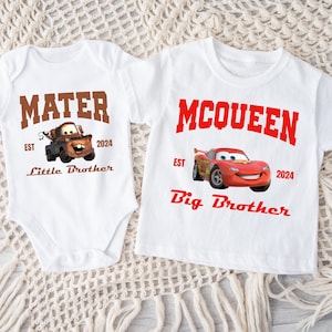 May include: White baby onesie and t-shirt featuring characters from the movie Cars. The onesie has "MATER" in brown text with a cartoon image of Mater and the text "Little Brother". The t-shirt has "MCQUEEN" in red text with a cartoon image of Lightning McQueen and the text "Big Brother".