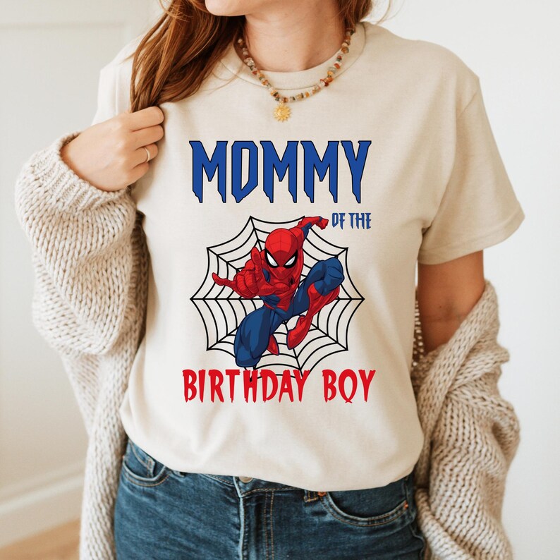 May include: A white t-shirt with the text "Mommy of the Birthday Boy" in blue and red letters. A cartoon image of Spiderman in a web is above the text.