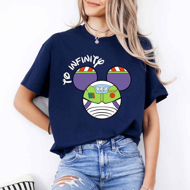 May include: A navy blue t-shirt with a white Mickey Mouse head design. The Mickey Mouse ears are purple and green with a Buzz Lightyear face in the center. The text "To Infinity" is printed above the Mickey Mouse head.