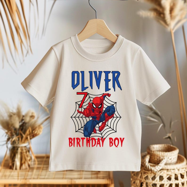 May include: White t-shirt with a red and blue Spiderman graphic, a web, and the text "Oliver 7 Birthday Boy".