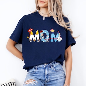 K&ouml;nnte beinhalten: Ein marineblaues T-Shirt mit einem Aufdruck der Toy Story-Charaktere, die das Wort "MOM" buchstabieren.