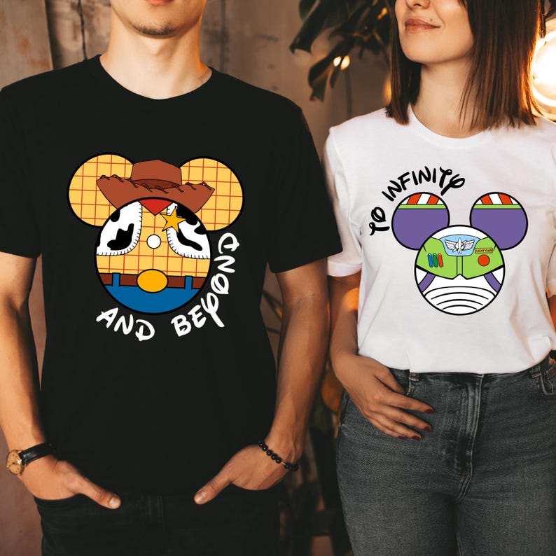 May include: Two t-shirts with a cartoon design. The black t-shirt has a cartoon image of Woody from Toy Story with the text "And Beyond". The white t-shirt has a cartoon image of Buzz Lightyear from Toy Story with the text "To Infinity".